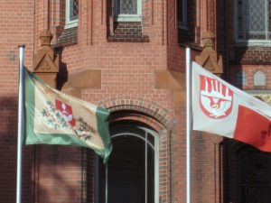 Die Gildefahne neben der Neumünsteraner Stadtflagge vor dem Rathaus